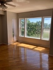 unfurnished room with ceiling fan, wood-type flooring, and a wealth of natural light