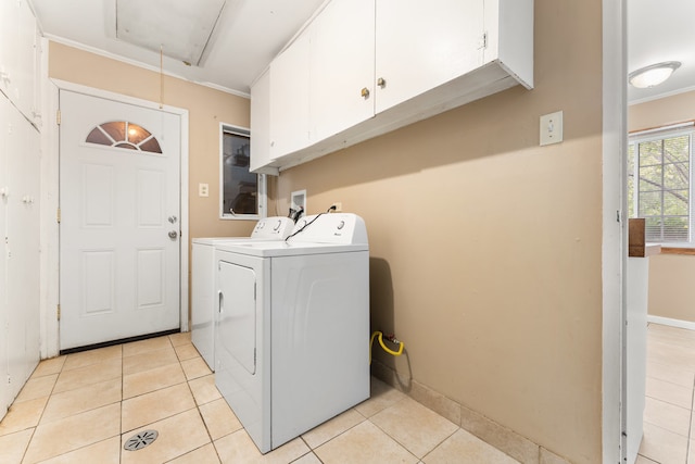 clothes washing area featuring washer and clothes dryer, cabinets, ornamental molding, and light tile patterned flooring