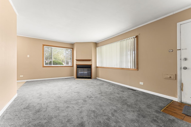 unfurnished living room featuring ornamental molding and carpet