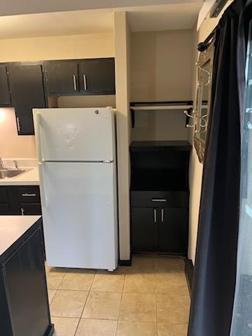 kitchen with white refrigerator, sink, and light tile patterned floors