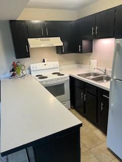 kitchen with white appliances, exhaust hood, light tile patterned floors, and sink