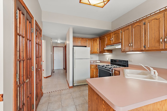 kitchen with sink, white refrigerator, kitchen peninsula, and black range with gas cooktop