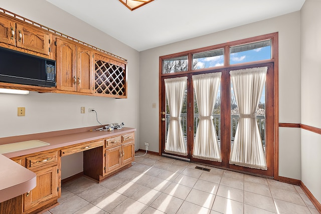 kitchen with built in desk, black microwave, and light tile patterned floors