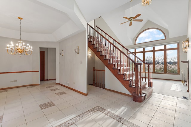 stairs with tile patterned floors, high vaulted ceiling, and ceiling fan with notable chandelier