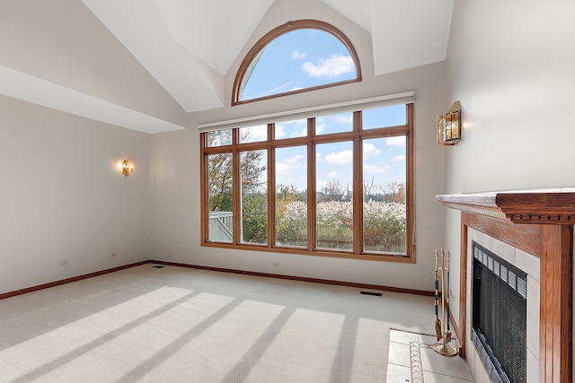 unfurnished living room with a tile fireplace, light carpet, and high vaulted ceiling