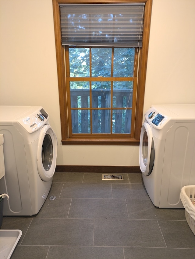 washroom with washer and clothes dryer and dark tile patterned floors