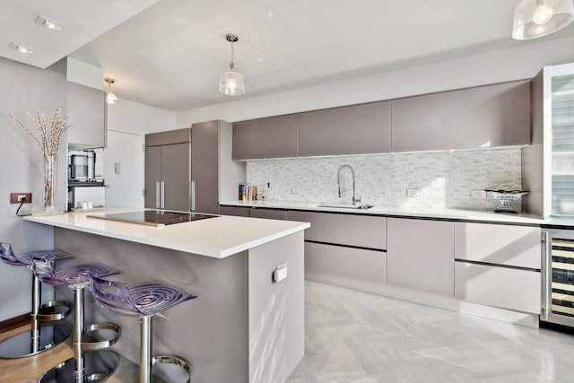 kitchen featuring a breakfast bar, sink, gray cabinetry, decorative light fixtures, and black electric cooktop