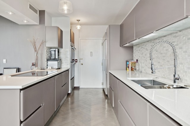 kitchen with backsplash, gray cabinets, hanging light fixtures, and sink