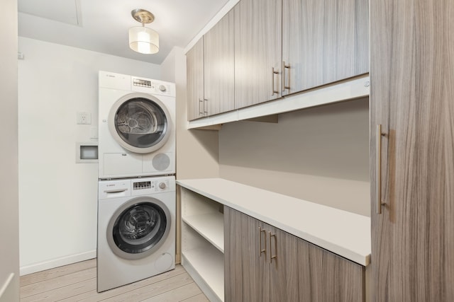 washroom with cabinets, stacked washer / dryer, and light hardwood / wood-style floors