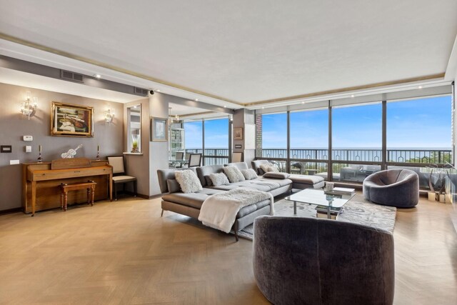 living room with a water view, a wall of windows, and parquet floors