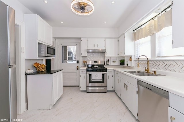 kitchen with appliances with stainless steel finishes, tasteful backsplash, sink, and white cabinets