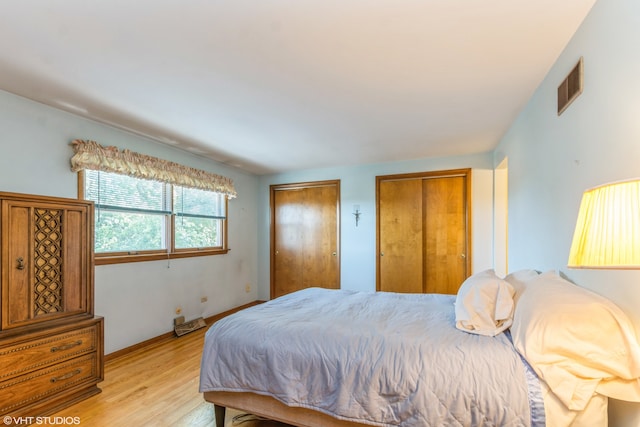 bedroom with light hardwood / wood-style flooring and two closets