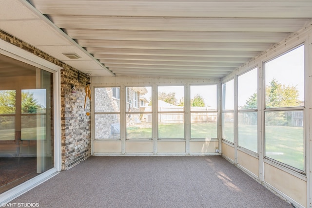 unfurnished sunroom featuring lofted ceiling with beams and plenty of natural light