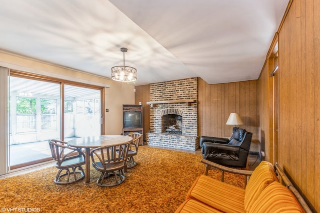 dining space featuring a brick fireplace, wooden walls, and an inviting chandelier