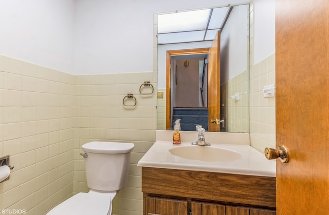 bathroom with tile walls, vanity, and toilet