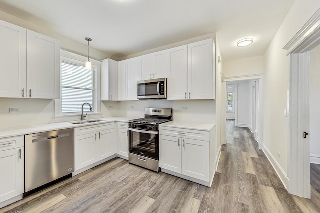 kitchen featuring stainless steel appliances, white cabinets, hanging light fixtures, and sink