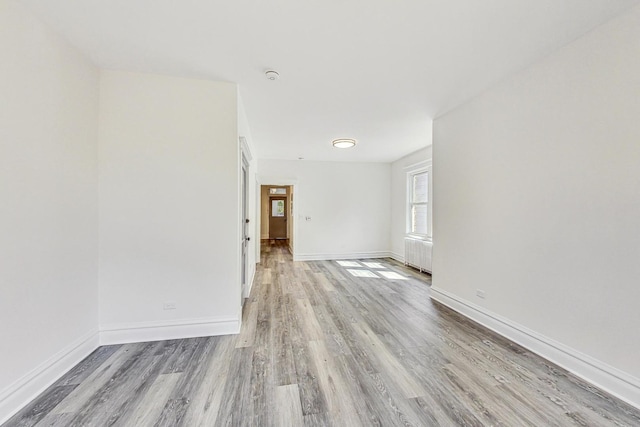 empty room with radiator heating unit and light hardwood / wood-style floors