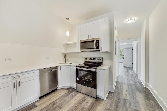 kitchen with sink, white cabinets, light hardwood / wood-style flooring, stainless steel appliances, and decorative light fixtures