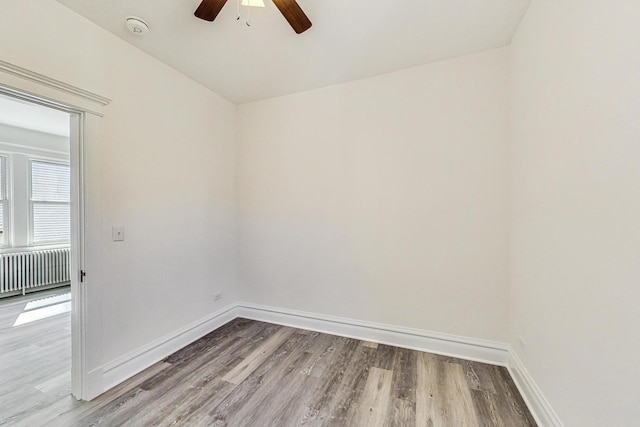 empty room featuring radiator, ceiling fan, and hardwood / wood-style flooring