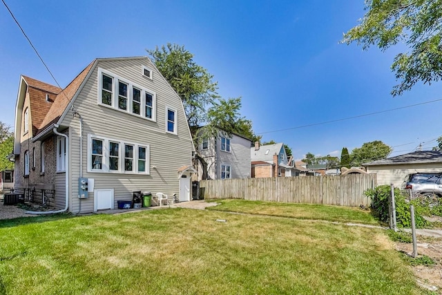 rear view of house with cooling unit and a yard