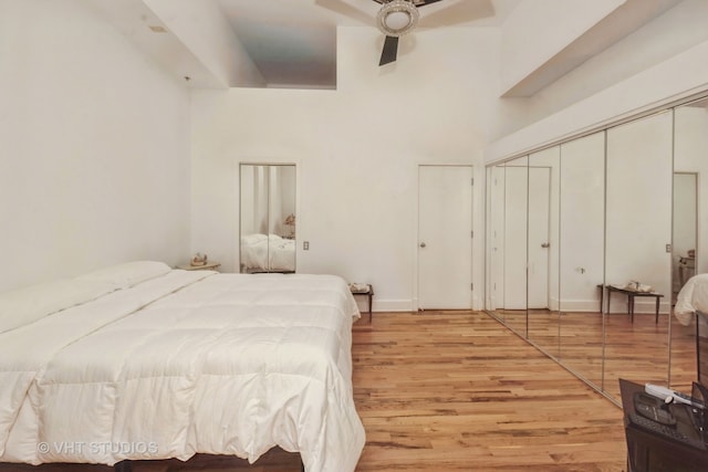 bedroom featuring a high ceiling, ceiling fan, a closet, and light hardwood / wood-style flooring