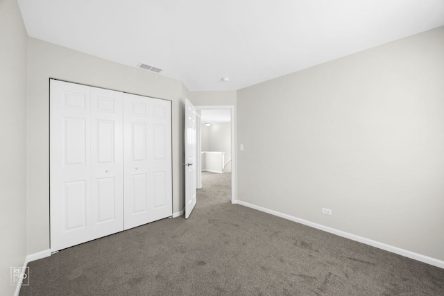 unfurnished bedroom featuring a closet and dark carpet