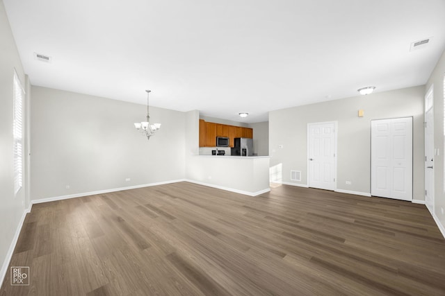 unfurnished living room featuring a chandelier and dark hardwood / wood-style floors