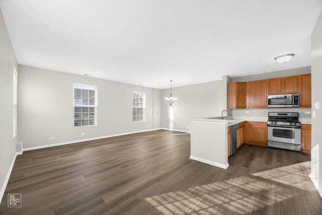 kitchen featuring sink, hanging light fixtures, an inviting chandelier, kitchen peninsula, and appliances with stainless steel finishes