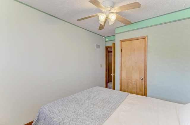 bedroom with ceiling fan and a textured ceiling