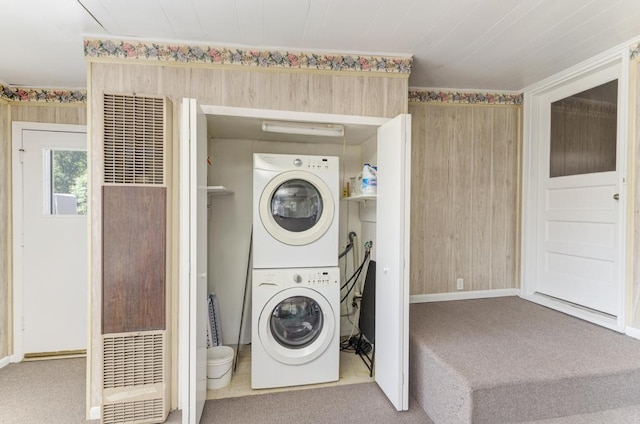 clothes washing area featuring stacked washer and clothes dryer and carpet