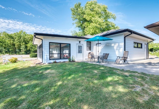 back of property with a lawn and a patio