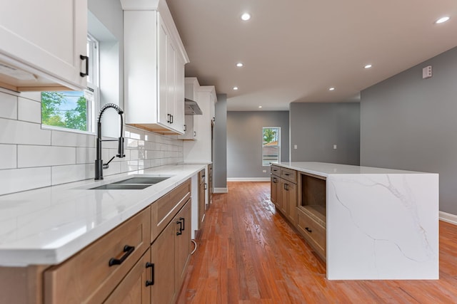 kitchen with light stone countertops, white cabinetry, and a kitchen island