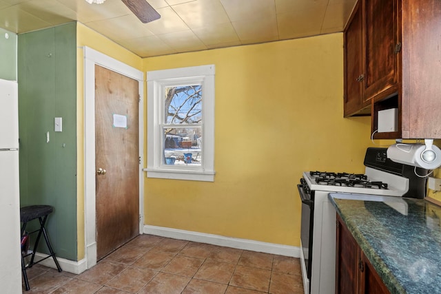 kitchen featuring ceiling fan, dark countertops, range with gas cooktop, and light tile patterned flooring