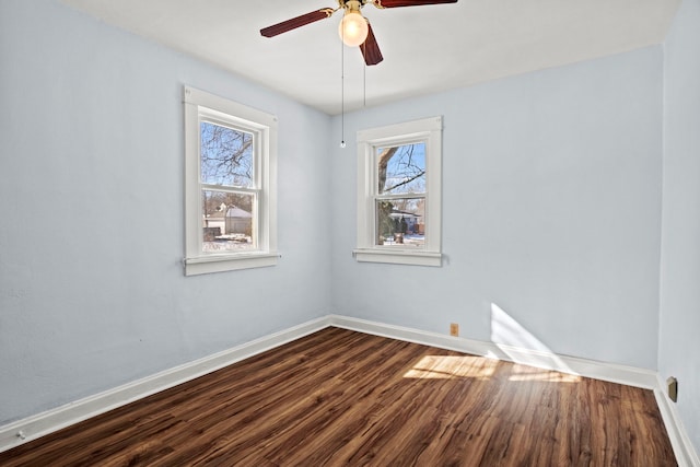 spare room featuring a healthy amount of sunlight, a ceiling fan, baseboards, and wood finished floors