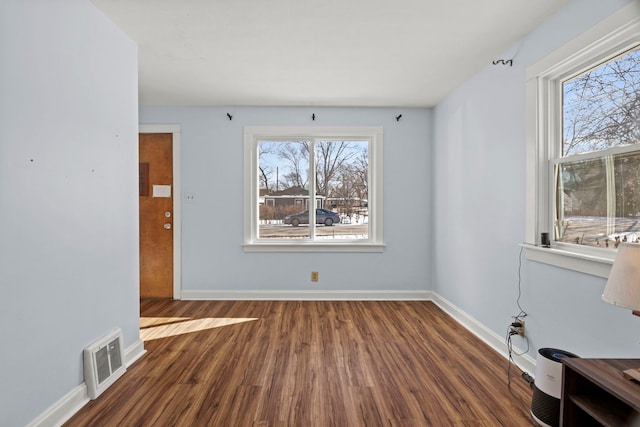 interior space with dark wood-type flooring, visible vents, and baseboards