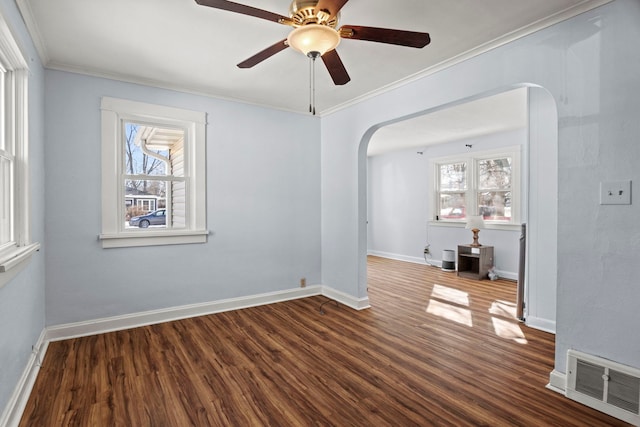 empty room featuring visible vents, arched walkways, crown molding, and wood finished floors