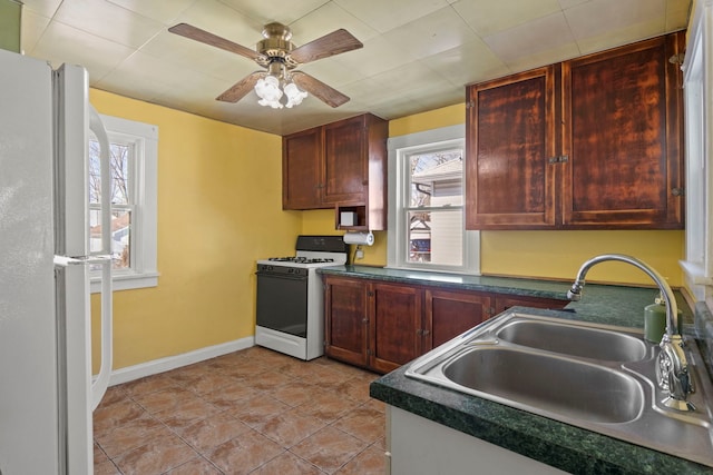 kitchen featuring white appliances, dark countertops, a sink, and a healthy amount of sunlight