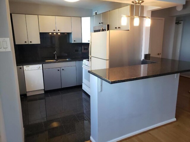 kitchen featuring white cabinets, sink, white appliances, a kitchen bar, and decorative backsplash