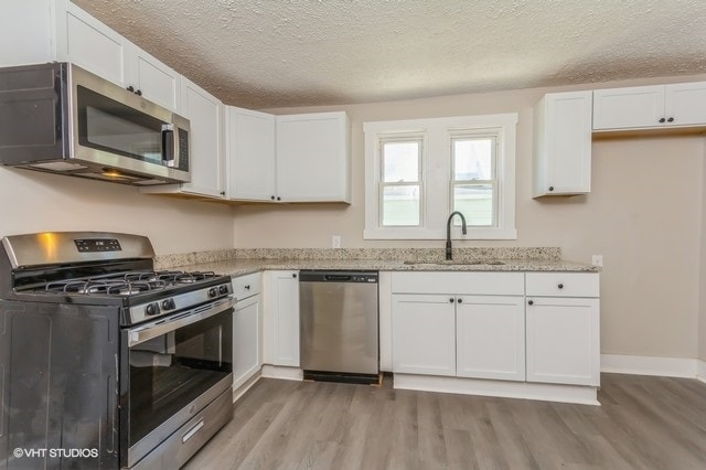 kitchen featuring stainless steel appliances, white cabinetry, and sink