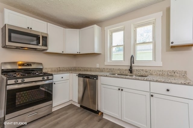 kitchen featuring a textured ceiling, sink, white cabinetry, stainless steel appliances, and dark hardwood / wood-style flooring