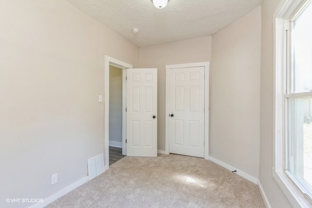 unfurnished bedroom with a textured ceiling and carpet flooring