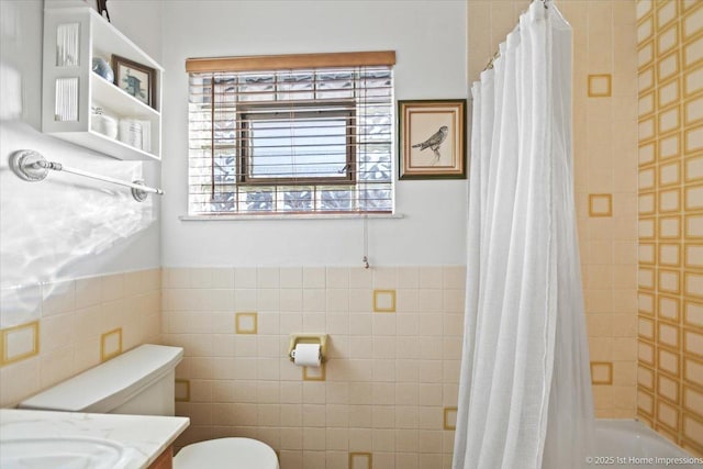 bathroom with toilet, vanity, and tile walls