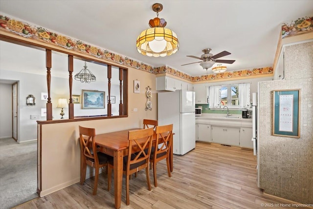 dining room featuring sink, light wood-type flooring, and ceiling fan