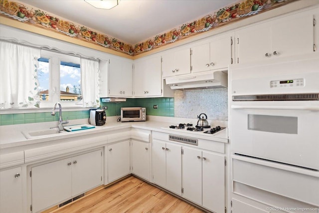 kitchen with sink, light wood-type flooring, white appliances, and white cabinets