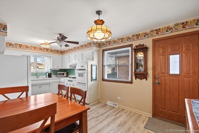 dining room with sink, light hardwood / wood-style flooring, and ceiling fan