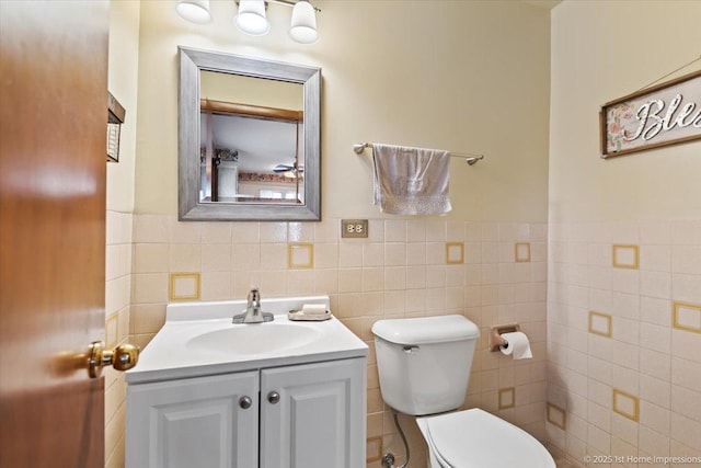 bathroom with toilet, tile walls, and vanity