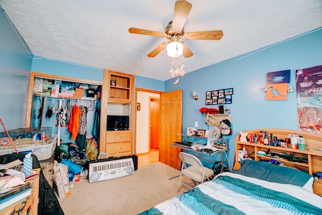 carpeted bedroom with a textured ceiling, ceiling fan, and a closet