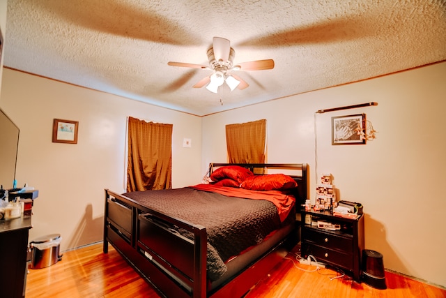 bedroom with ceiling fan, a textured ceiling, and light hardwood / wood-style floors