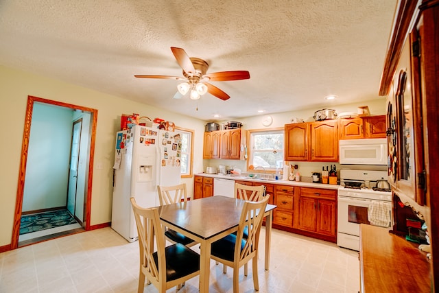 interior space with a textured ceiling, white appliances, ceiling fan, and sink