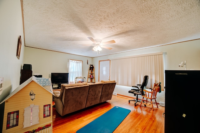 living room with ceiling fan, hardwood / wood-style flooring, and a textured ceiling